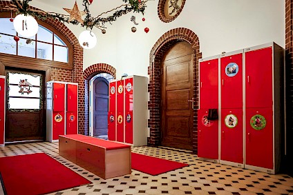 The charming hallway with a dressing area and an individual red locker for each child