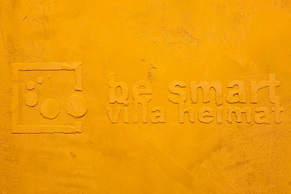Special relief of the Villa Heimat logo on a yellow wall
