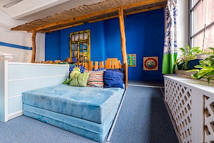 A large mattress and many colorful cushions in the Olympia room invite you to relax