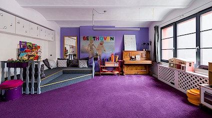 The music corner in the Beethoven room with fluffy violet carpets, drums, a piano and other instruments